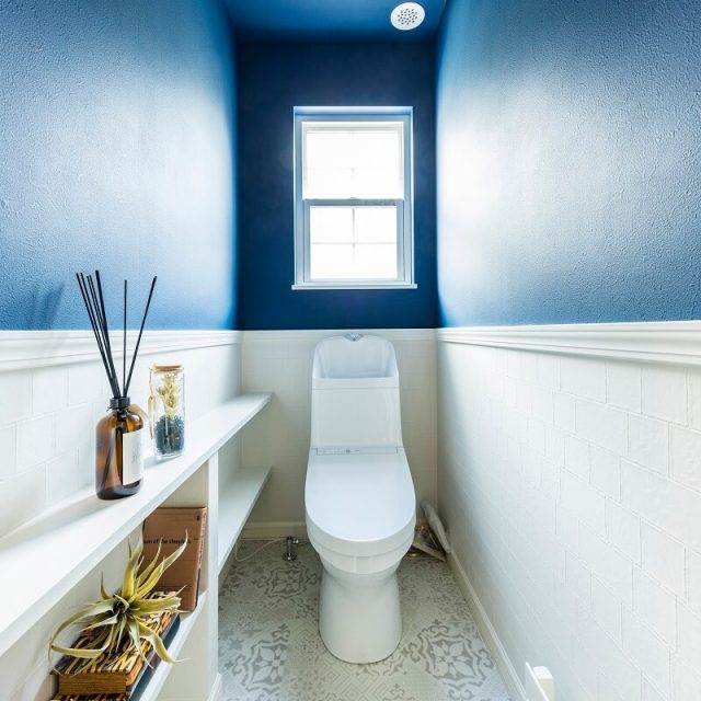 上下で見切りをつけたトイレ。深いブルーの壁紙がキレイ。