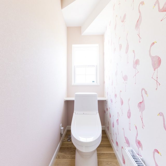 フラミンゴ柄の壁紙を貼ったトイレは、階段下のスペースを有効活用。